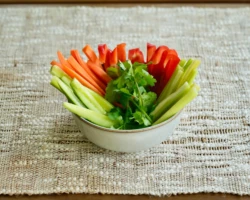 Crisp vegetable sticks made from carrots, cucumbers, celery, and red bell peppers, beautifully arranged and garnished with fresh cilantro. A healthy and refreshing snack or appetizer. A bowl of fresh vegetable sticks, including carrots, cucumbers, celery, and red bell peppers, garnished with fresh cilantro